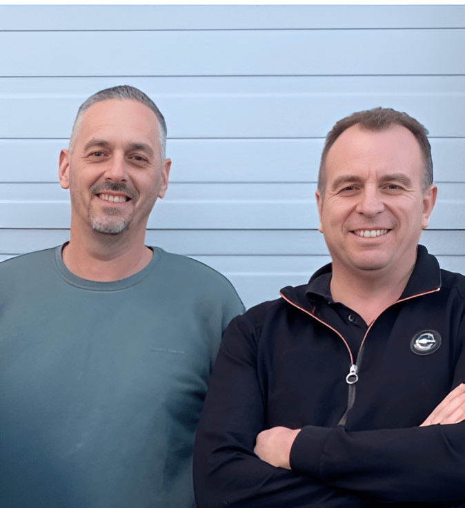 Deux hommes souriants debout devant un mur clair, représentant l’équipe de l’entreprise. Emmanuel COSNARD et Christophe CORDIER