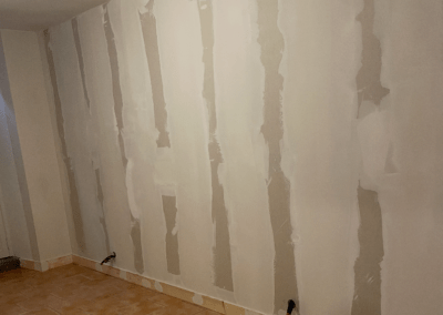 Mur intérieur en rénovation avec bandes d’enduit appliquées entre les plaques de plâtre en préparation pour la finition.